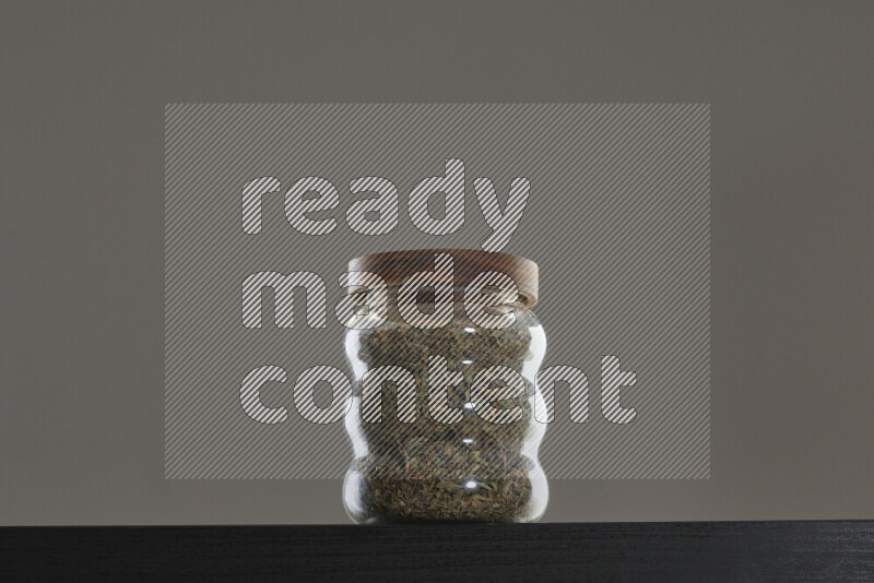 Dried basil in a glass jar on black background