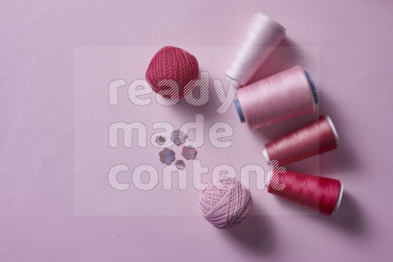 A pink collection of sewing and tailoring tools arranged on a pink background