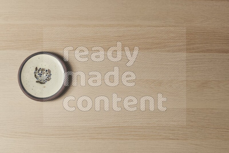 A decorative pottery plate on light wooden background