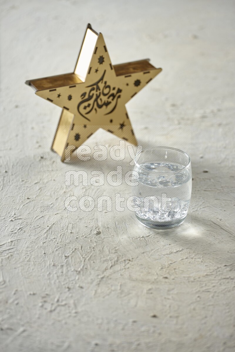 A wooden golden star lantern with different drinks, dates, nuts, prayer beads and quran on textured white background