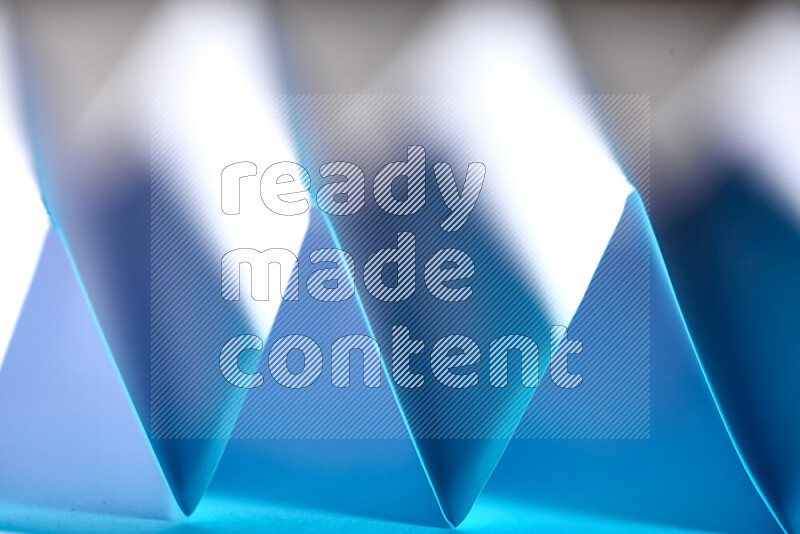 A close-up abstract image showing sharp geometric paper folds in blue gradients
