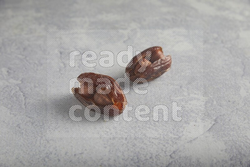 Two hazulnut stuffed dates on light grey background