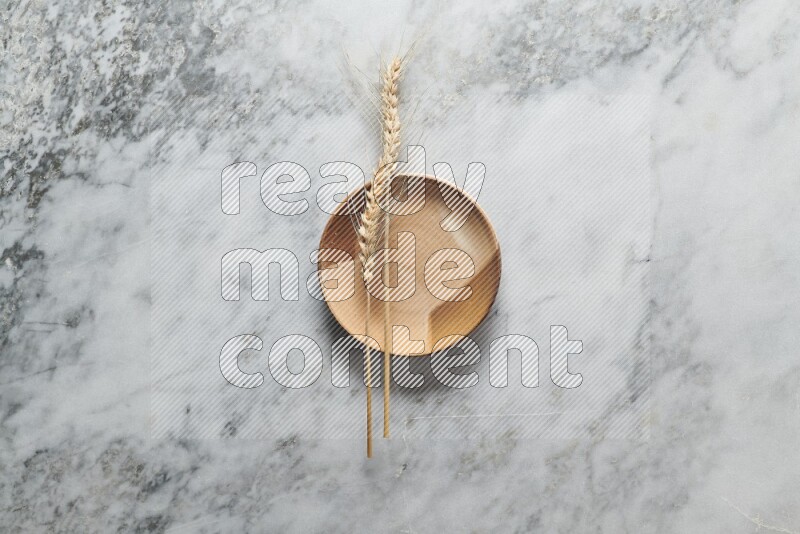 Wheat stalks on multicolored pottery plate on grey marble background