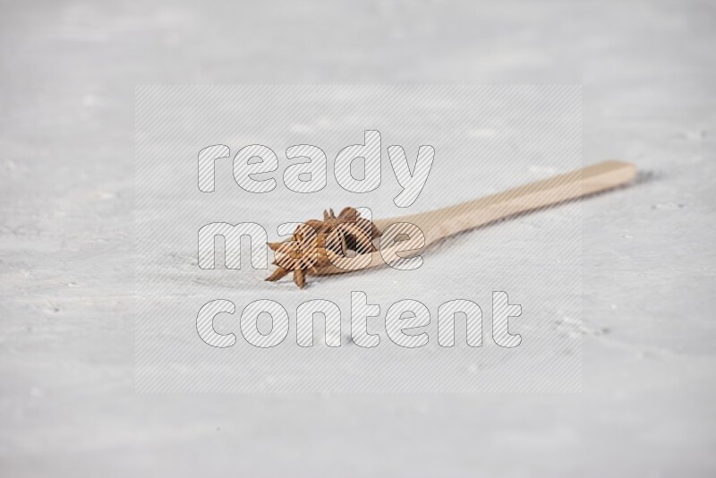 Star Anise in a wooden spoon on white flooring