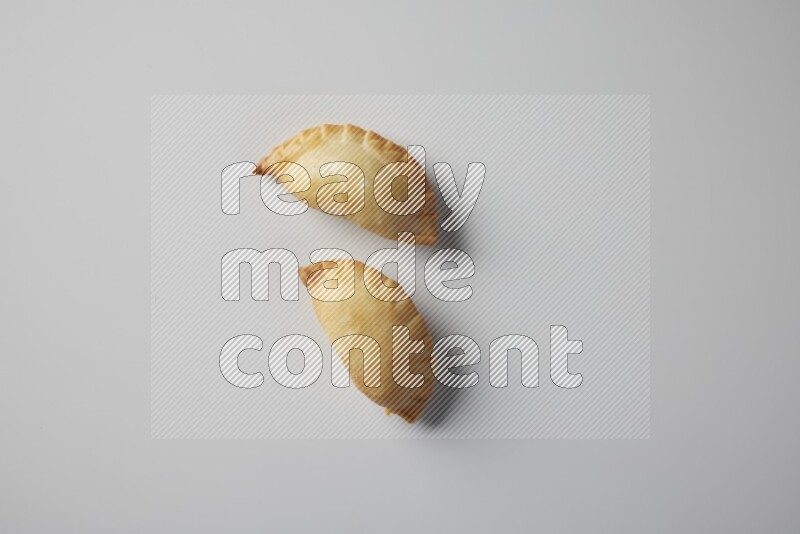 Two fried sambosa from a top angle on a white background