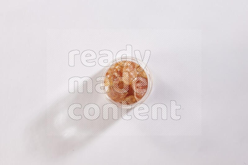 وعاء زجاجي ممتلئ بقطع الصمغ العربي علي خلفية بيضاء