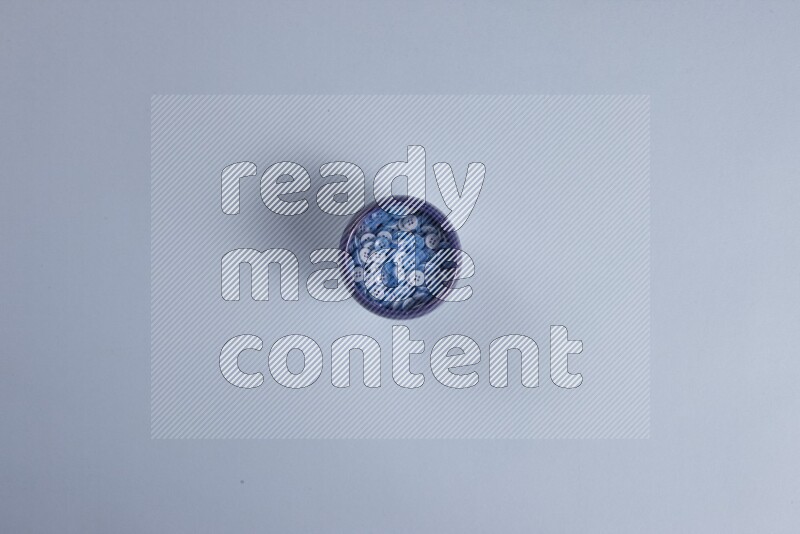 Multicolored pottery bowls full of colored buttons on blue background