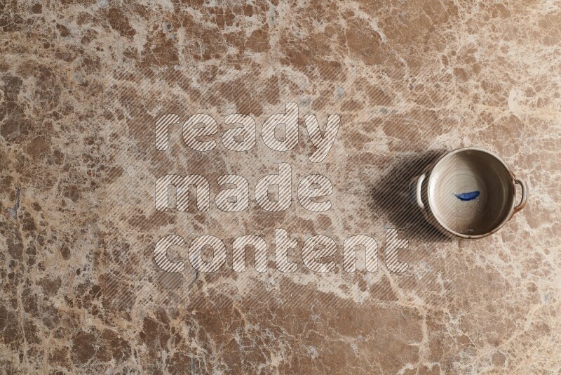 A multicolored pottery bowl on beige marble background