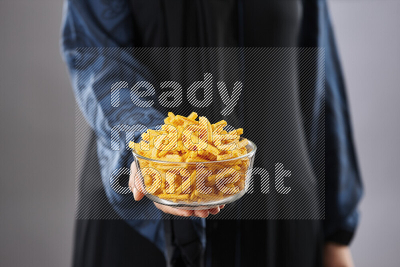 Woman in abaya holding different kinds of snacks in different positions