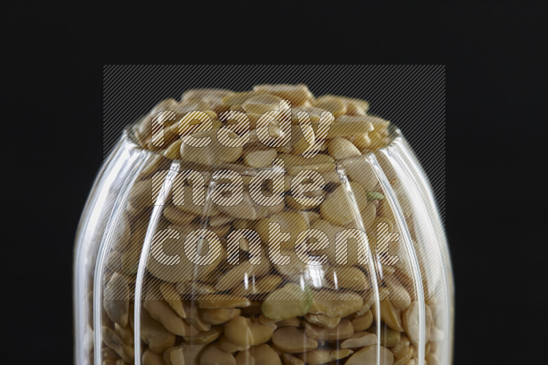 Crushed beans in a glass jar on black background