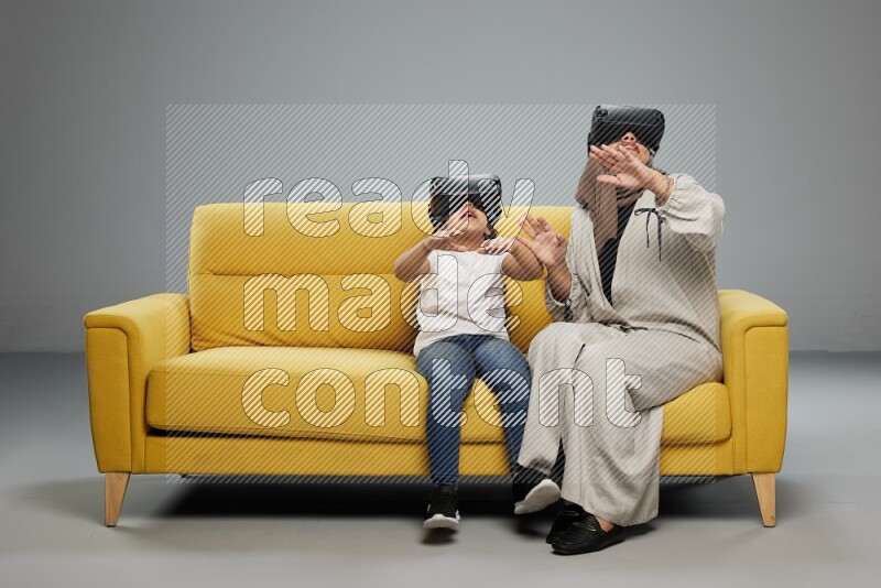 A girl and her mother sitting playing with VR on gray background