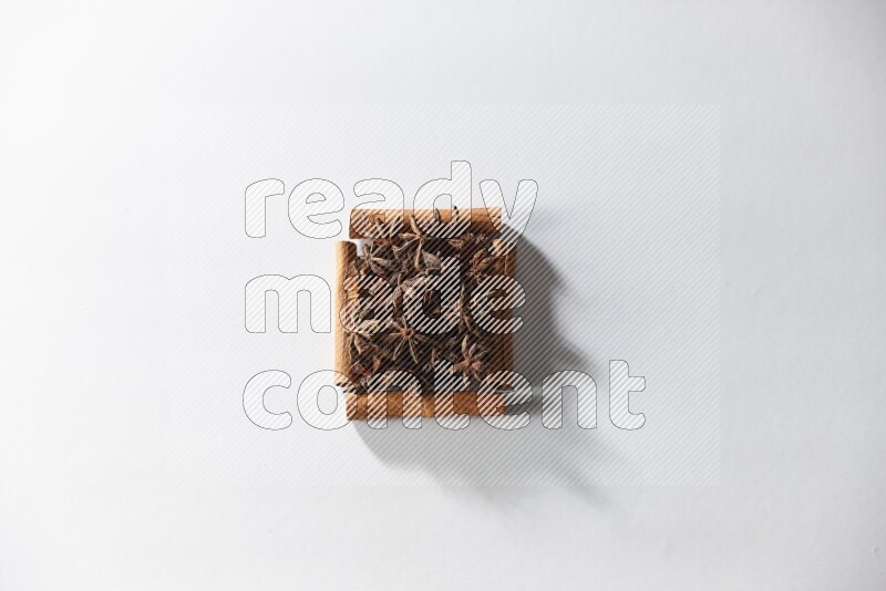 A single square of cinnamon sticks full of star anise on white flooring