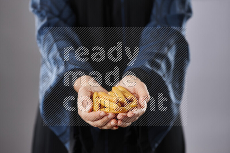 Woman in abaya holding different kinds of snacks in different positions