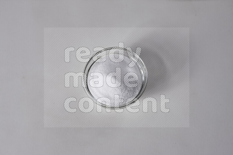 A glass bowl full of fine table salt on white background
