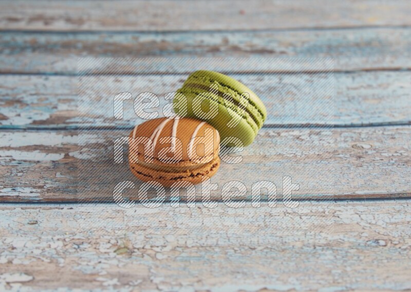 45º Shot of of two assorted Brown Irish Cream, and Green Pistachio macarons  on light blue background