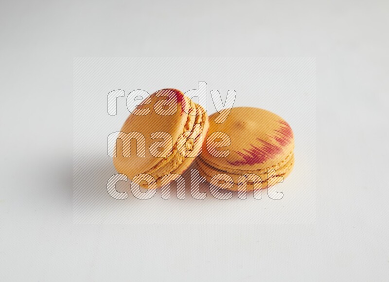 45º Shot of two orange Exotic macarons on white background