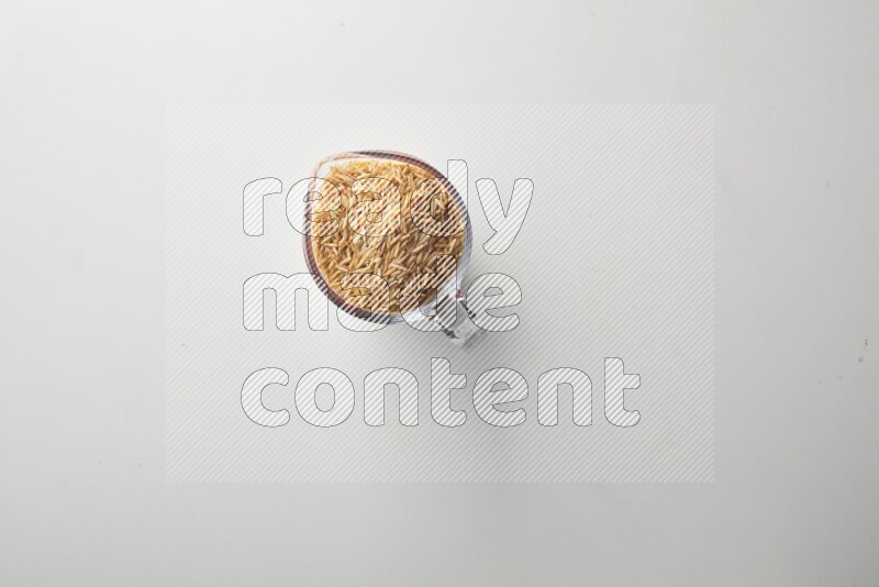 Top-view shot of long grain brown rice in a container on white background