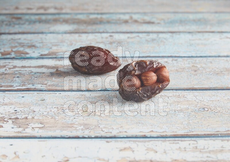two hazelnuts stuffed madjoul dates on a light blue wooden background
