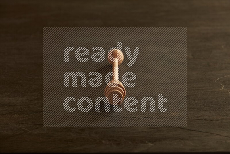 Wooden honey dipper on black slate background