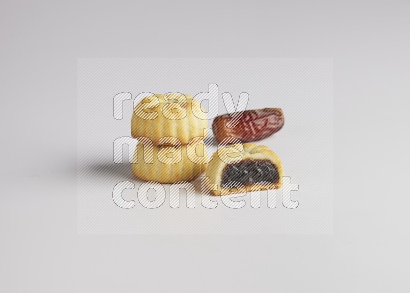 Three Pieces of Maamoul filled with date one of them is cut direct on white background