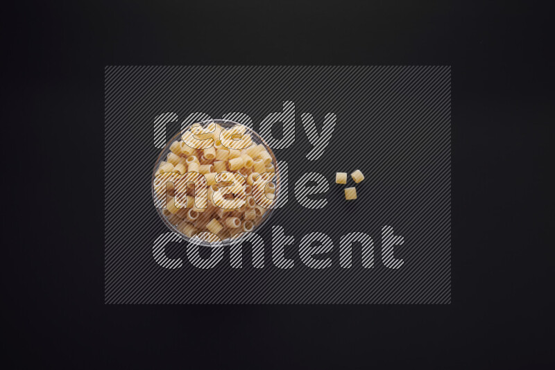 Big rings pasta in a glass bowl on black background
