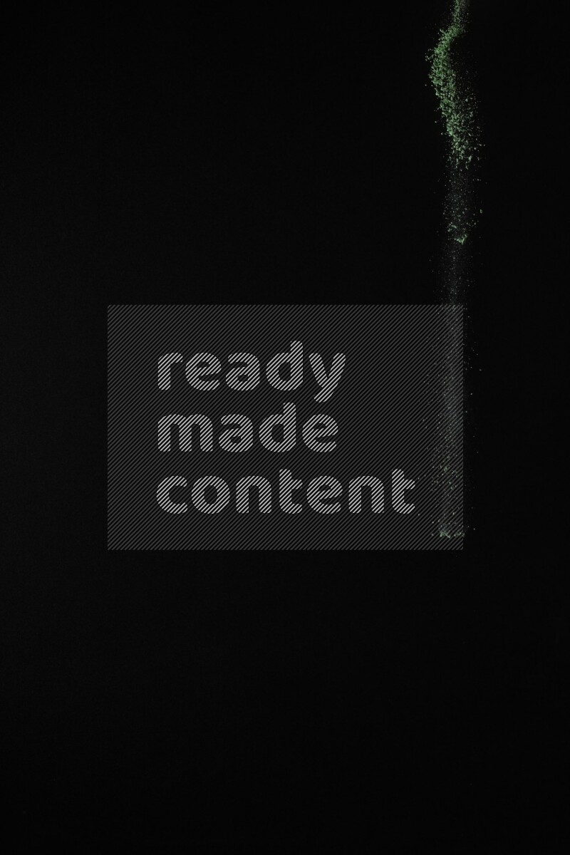 A side view of green powder explosion on black background