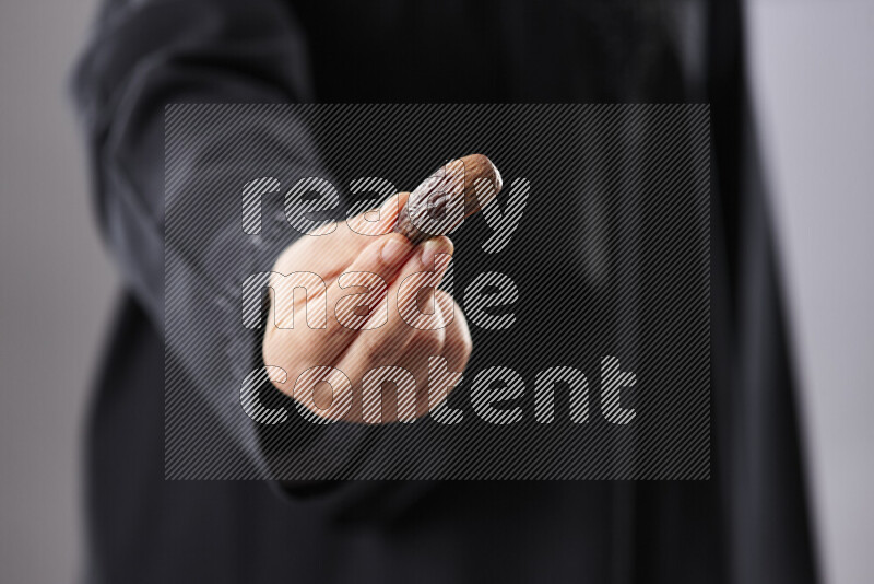 امرأة ترتدي عباءة تحمل أنواع مختلفة من التمر في أوضاع متعددة