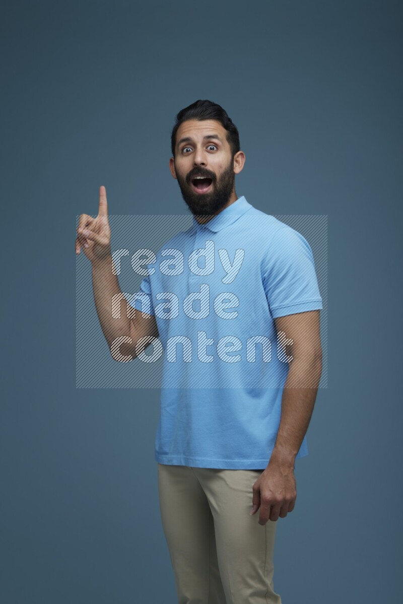 A man pointing  in a blue background wearing a Blue shirt
