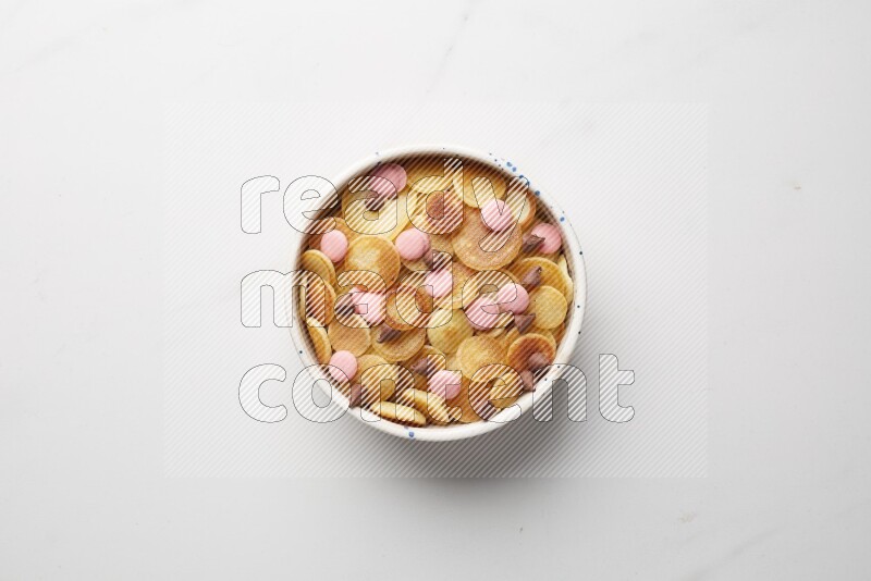 Top-view shot of mixed chocolate chips cereal pancakes in a round bowl on white background