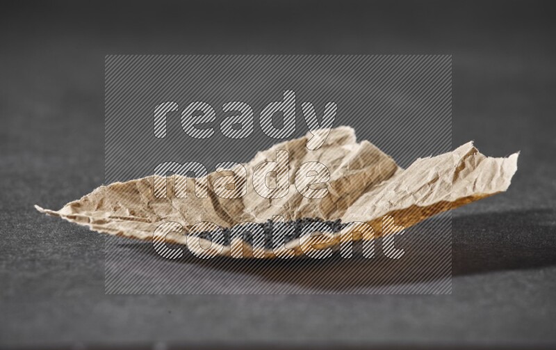 بذور حبة البركة في قطعة من الورق علي خلفية سوداء