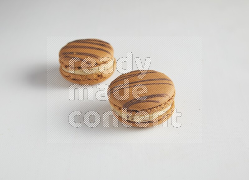 45º Shot of two light brown  Almond Cream macarons on white background