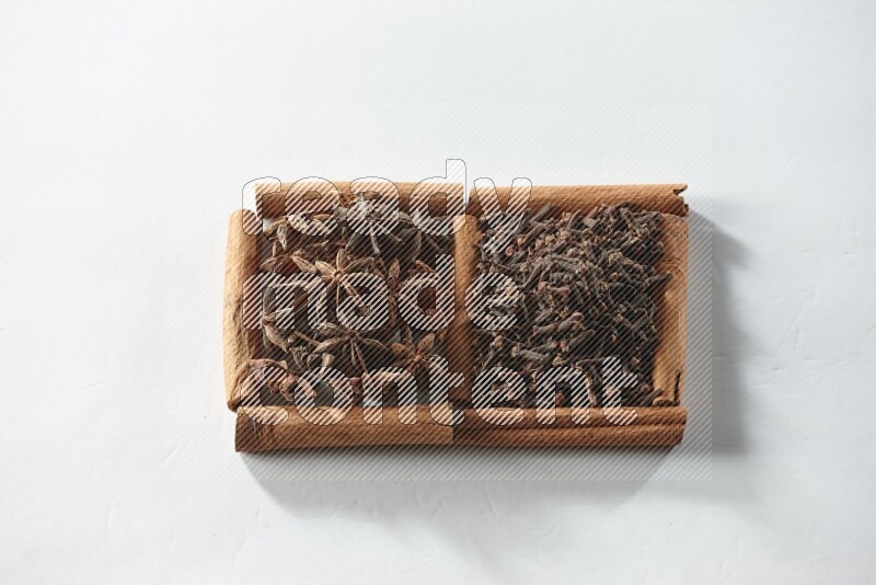 2 squares of cinnamon sticks full of cloves and star anise on white flooring