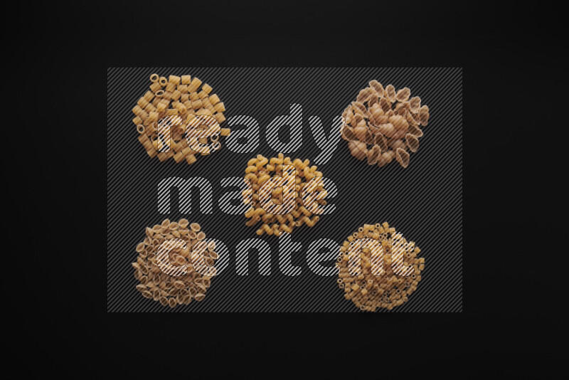 Different pasta types in bunches on black background