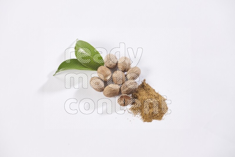 Nutmeg whole seeds with nutmeg powder beside it on a white flooring