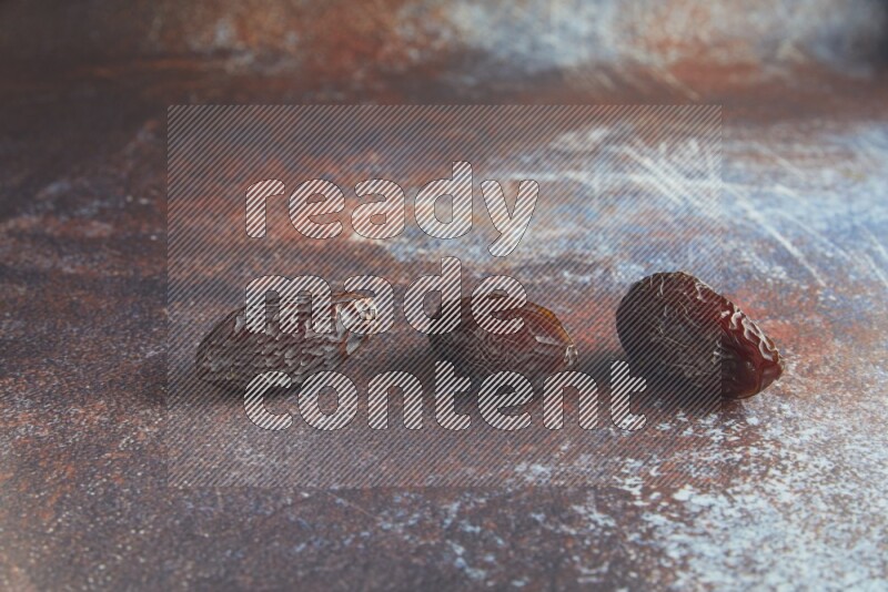 three madjoul dates on a rustic reddish background