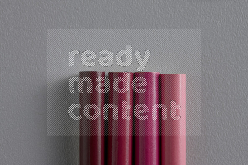 A collection of sharpened colored pencils arranged showcasing a gradient of pink hues on grey background