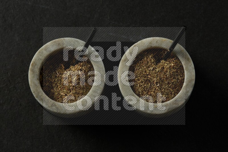 black and white round marble containers filled with herbs on gray textured countertop