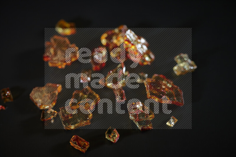 Transparent orange fragments of glass scattered on a black background