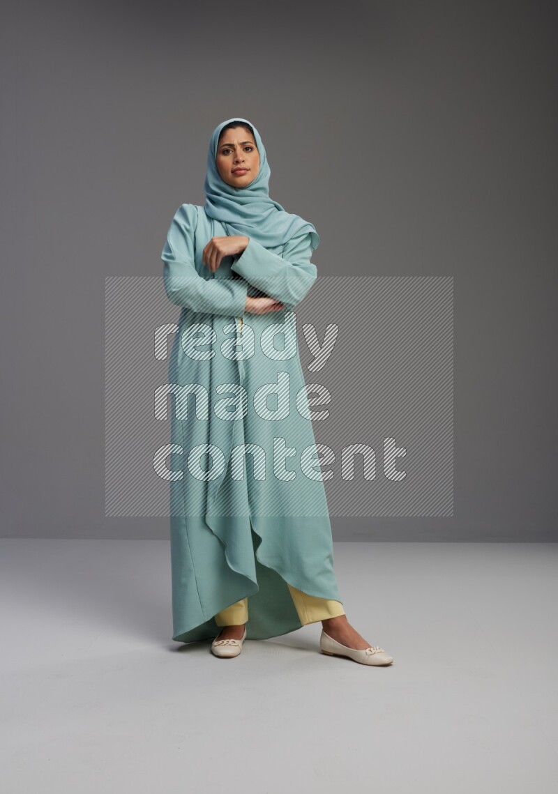 Saudi Woman wearing Abaya standing interacting with the camera on Gray background