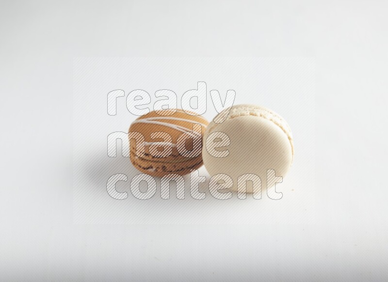 45º Shot of of two assorted Brown Irish Cream, and White Caramel fleur de sel macarons on white background