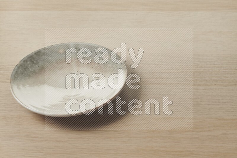 A multicolored pottery plate on light wooden background