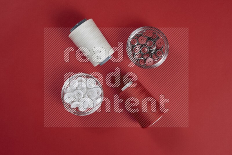 A white collection of sewing and tailoring tools arranged on a red background
