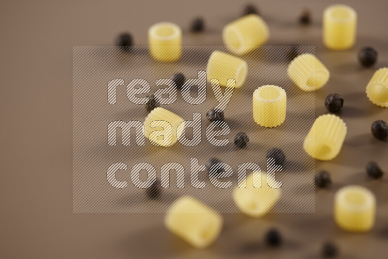 Raw pasta with different ingredients such as cherry tomatoes, garlic, onions, red chilis, black pepper, white pepper, bay laurel leaves, rosemary and cardamom on beige background