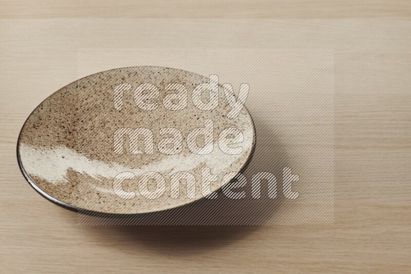 A beige pottery plate on light wooden background