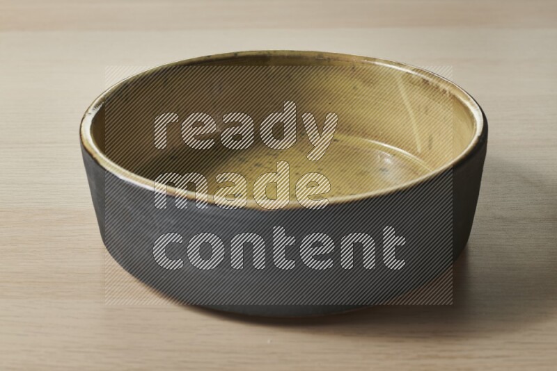 A multicolored pottery oven plate on light wooden background