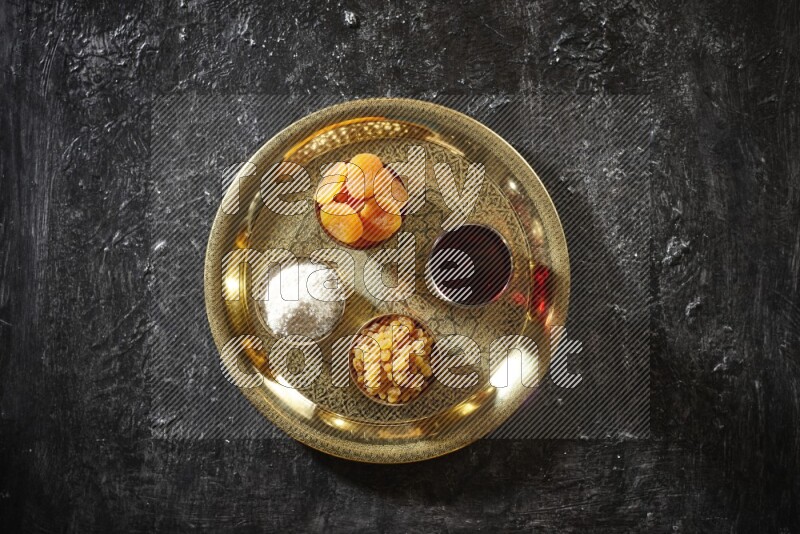 Dried fruits in metal bowls with Hibiscus on a tray in dark setup