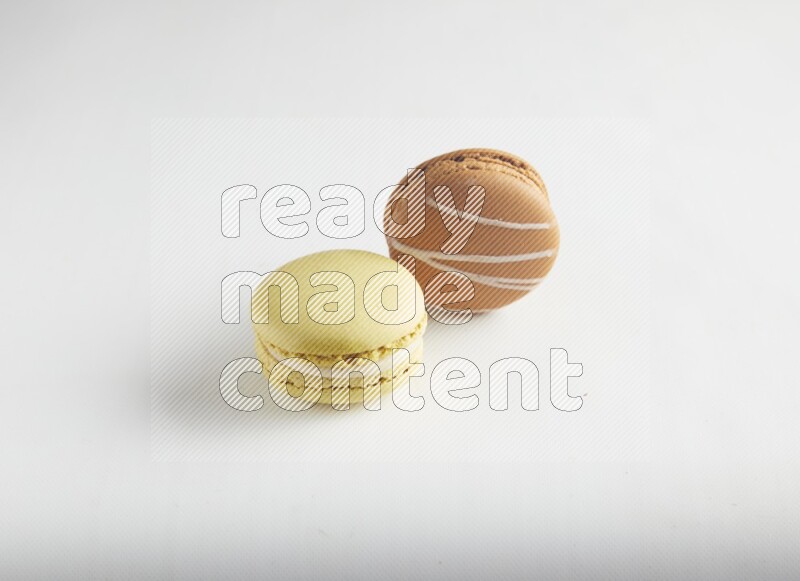 45º Shot of of two assorted Brown Irish Cream, and Yellow Lime macarons on white background