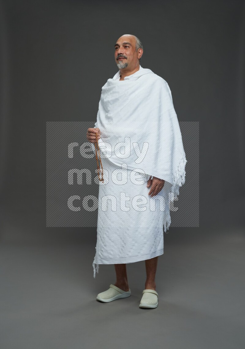 A man wearing Ehram Standing holding rosary on gray background