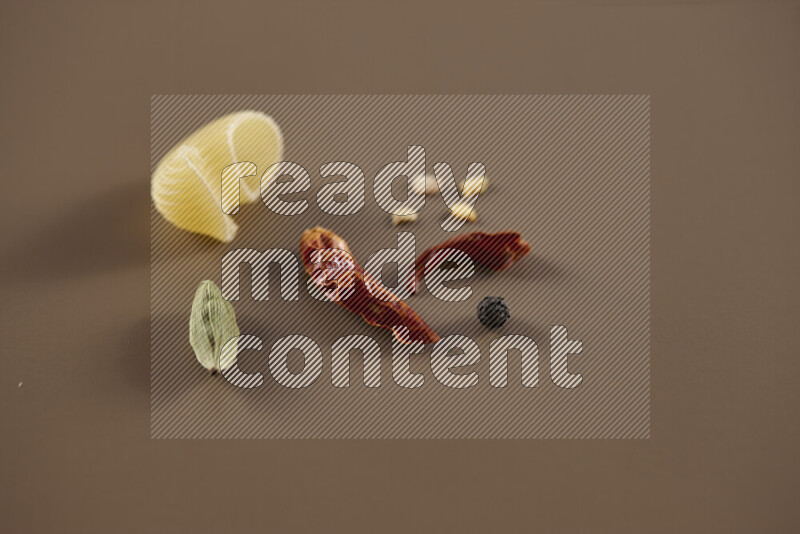 Raw pasta with different ingredients such as cherry tomatoes, garlic, onions, red chilis, black pepper, white pepper, bay laurel leaves, rosemary and cardamom on beige background