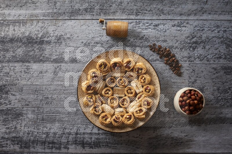 Oriental sweets in a pottery plate with nuts, coffee and honey in a dark setup